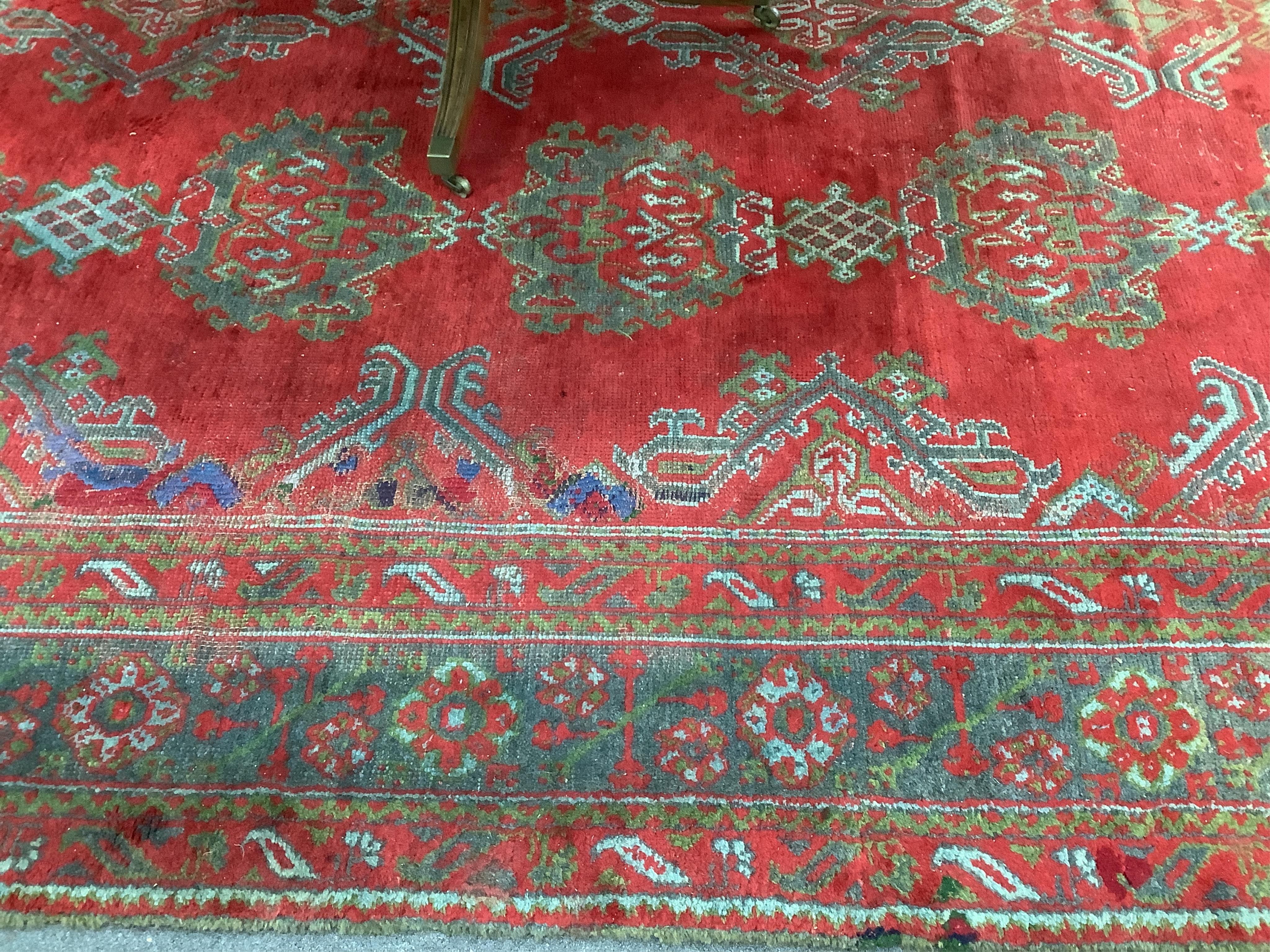 A large Turkish carpet, with triple row of stylised medallions on a red ground, multi bordered, 413 x 345cm. Condition